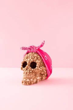 Tied pink bandana on skull head on pastel background. Minimalistic retro or scary halloween concept.