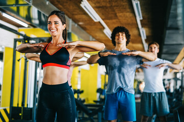 Group of fit people working out in a gym. Multiracial friends exercising together in fitness club.