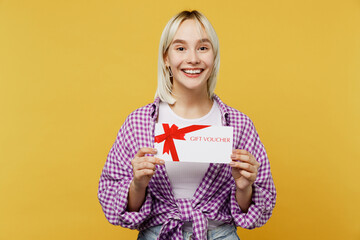 Young excited blonde woman 20s she wear pink tied shirt white t-shirt hold gift certificate coupon voucher card for store isolated on plain yellow background studio portrait. People lifestyle concept.