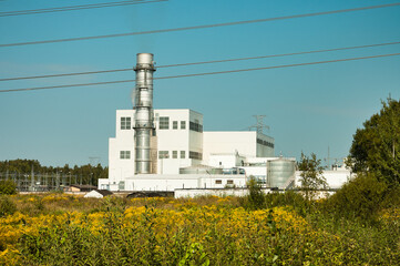 a power plant, a power plant on a blue sky background in the foreground is a green meadow