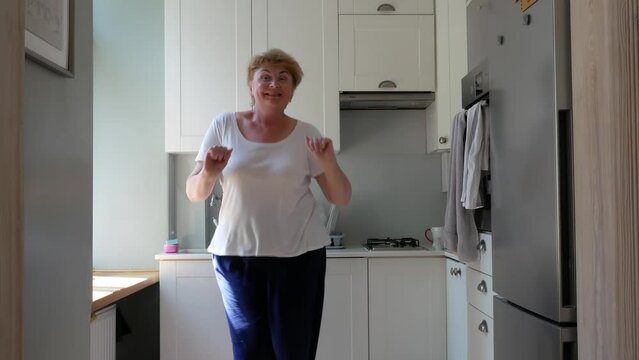 body positive blond middle-aged woman dancing in kitchen with frying pan and ladle, emotion image, cooking love concept