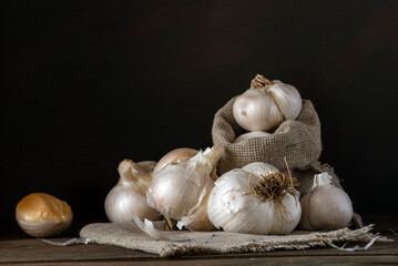 big Garlic Cloves and Bulb wooden table cooking on dark background. burlap sack cutting board copy space Close-up  rustic  still life spice Healthy organic antioxidant raw.