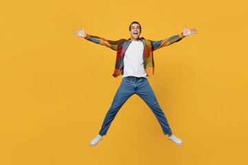 Fototapeta na wymiar Full size young carefree middle eastern man wear casual shirt white t-shirt jump high with outstretched hands like flying isolated on plain yellow background studio portrait People lifestyle concept.