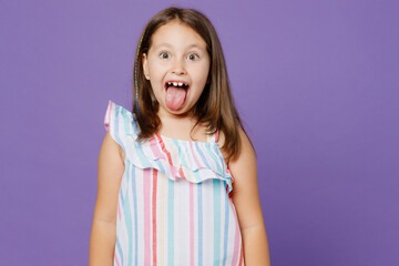 Little cool funny joyful positive kid child girl 5-6 years old wears striped dress look camera show tongue isolated on plain pastel light purple background. Mother's Day love family lifestyle concept.