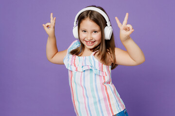 Little smiling happy kid child girl 5-6 years old wearing striped dress headphones listen music show v-sign isolated on plain pastel light purple background Mother's Day love family lifestyle concept