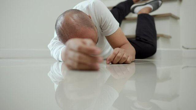 Man faints and collapses on the stairs of the house. He was injured in an accident and fell down the stairs. He was alone in the house not being helped by anyone. Broken bone. Home accident concept.