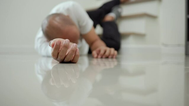 Man faints and collapses on the stairs of the house. He was injured in an accident and fell down the stairs. He was alone in the house not being helped by anyone. Broken bone. Home accident concept.