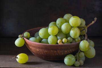 organic ripe seedless green grape clay ceramic dish bowl pot  wooden table Still life Close up rustic orange blue light.