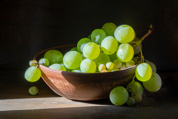 organic ripe seedless green grape clay ceramic dish bowl pot  wooden table Still life Close up rustic orange blue light.