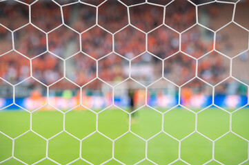 Detail of goal's net and football match in the background.