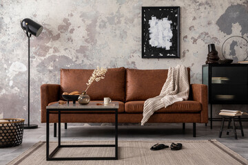 Interior design of loft industrial apartment with mock up poster frame, brown sofa, coffee table and black commode and personal accessories. Concrete gray wall. Home decor. Template.