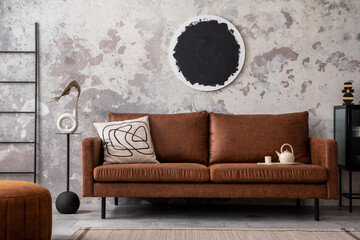 Contemporary design of living room interior with brown sofa, poster, pouf and personal accessories. Gray concrete wall. Home decor. Template.