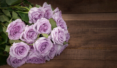 a bouquet of delicate purple roses on a background of dark wooden boards with a copy of the space