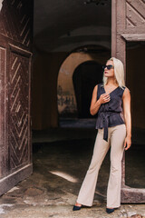 A young, slender blonde in beige pants and a black blouse walks the old streets of Lviv. Ukraine.