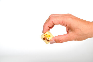 Demonstration of chocolate candie with nut or fruit filling, on the outstretched fingers of a female hand with a manicure.