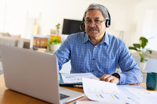 Senior biracial man using laptop and headset making video call