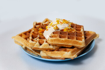 Orange Belgian waffles on  plate with yogurt