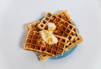 Orange Belgian waffles on  plate with yogurt