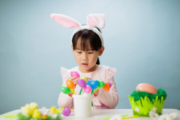 young girl making easter craft against plain background
