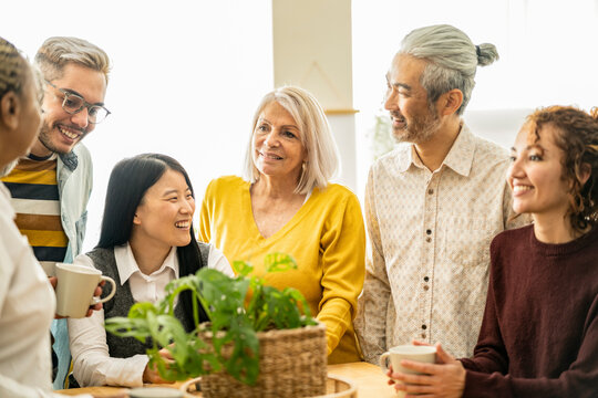 Multicultural Family Gathered In The Kitchen At Home, At The Adult Party, Birthday. Focus On Senior Woman With Gray Hair -