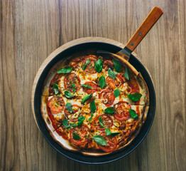 Tasty Homemade margherita pizza with with Tomatoes, Basil and Mozzarella Cheese on wooden background, top view.