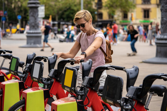 Red rental bikes Bicing on the parking station. Tourist woman use red bicycles with app. Barcelona, Spain - September 14, 2022