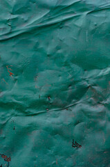 Crumpled sheet of metal with old green paint, grungy texture surface, close-up vintage background.