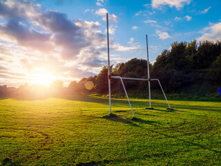 Small tall goal post on training field for rugby and Irish national games hurling, camogie, Gaelic football and soccer at sunset. Rich green and blue colors. Sun flare and blue sky. Sport area © mark_gusev