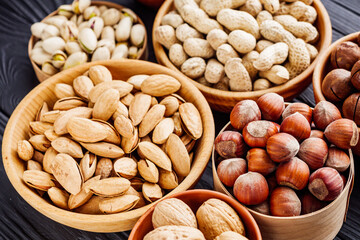 set of different nuts on a black rustic wooden background
