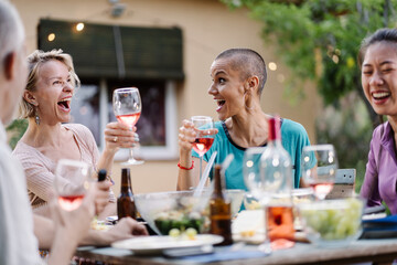 Female friends having fun time together at dinner, drinking wine and laughing - Happy women