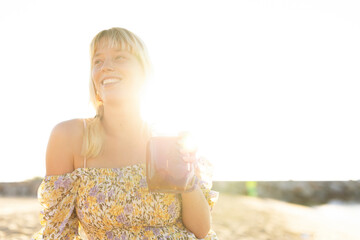 Cheerful young woman enjoy at tropical sand beach. Girl drinking fresh juice