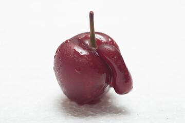 Red black cherry on white background with water drops. With appendix. Ugly crooked fruit.
