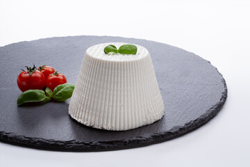 whole cottage cheese with fresh tomatoes on black stone cutting board