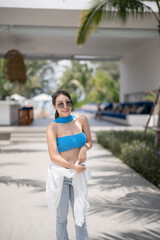 Woman in blue top and jeans walking in tropical resort hotel.