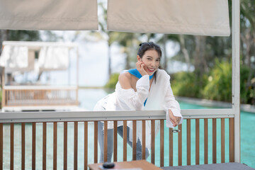 Sexy woman relaxing near sunbed cabana by the pool at hotel resort.