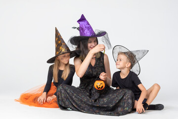 A happy family, a mother and children in creepy witch and sorcerer costumes holding a...