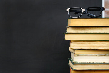 Books and glasses on a blackboard background