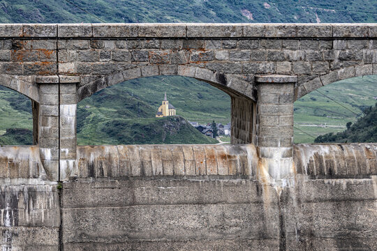 View of the small church of Sant'Anna through the Morasco lake dam in the village of Riale in Formazza Valley, in Verbano-Cusio-Ossola, Italy