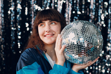 Young sporty woman 80 and 90's style. 90s fashion positive girl at disco party with disco ball in...