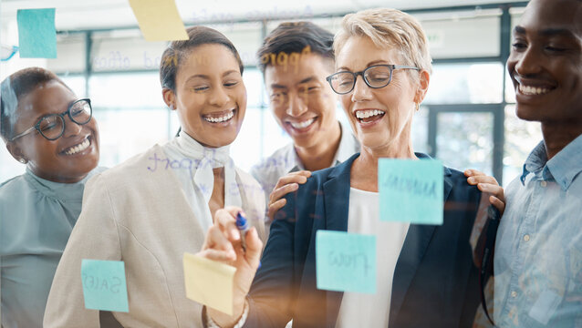 Teamwork, Planning And Strategy With A Business Woman, Manager Or CEO Working With A Team On A Glass Wall And Sticky Notes. Collaboration, Learning Or Development With A Group In An Office For Growth