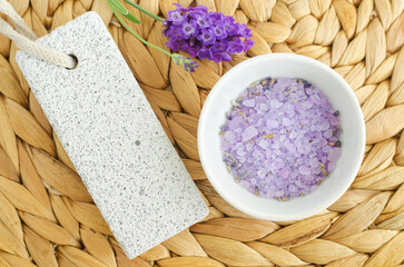 Fototapeta na wymiar Small white bowl with purple lavender crystal bath salt (foot soak) and pumice stone. Homemade pedicure, spa and beauty treatment recipe.