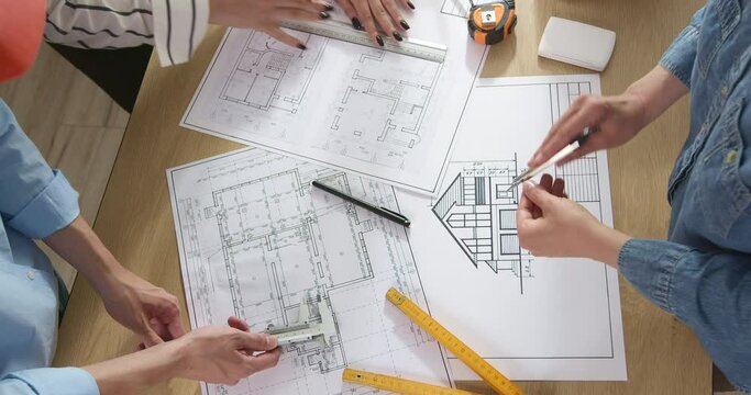 Colleagues architects are working on a construction project. Design drawings on the desktop of builders.