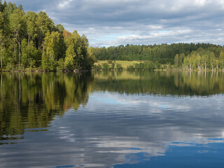 Fototapeta na wymiar Typical autumn landscape in the Republic of Karelia, northwest Russia. Lake in calm weather, forest, clouds on the sky