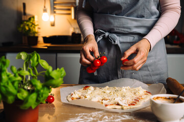 woman prepares pizza in home kitchen