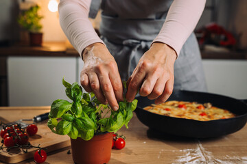 close up of woman picking basil for decorating pizza