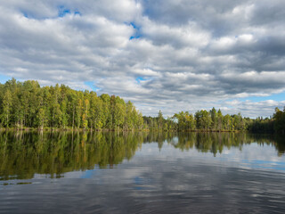 Typical autumn landscape in the Republic of Karelia, northwest Russia. Lake in calm weather, forest, clouds on the sky