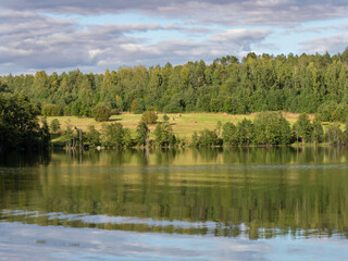 Autumn landscape in the Republic of Karelia, northwest Russia. Lake in calm weather, forest, haystacks on the field