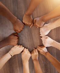 Hands, collaboration and motivation with the fists of a team in a circle or huddle on a wooden...