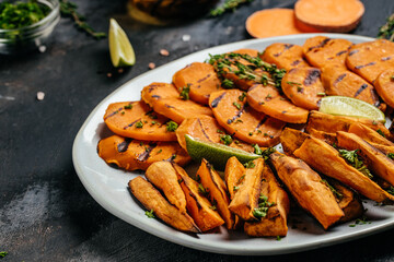 Sweet potato fries with herbs on dark background. Long banner format. top view