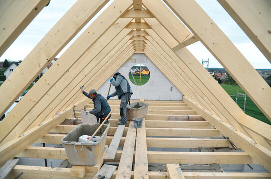 Zwei Handwerker arbeiten im Dachstuhl des Rohbaus eines neuen Einfamilienhauses, Copy Space